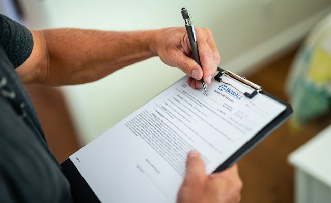 Person holding clipboard with Ekwall Restoration inspection document, emphasizing home inspection services and quality assurance in Payson.
